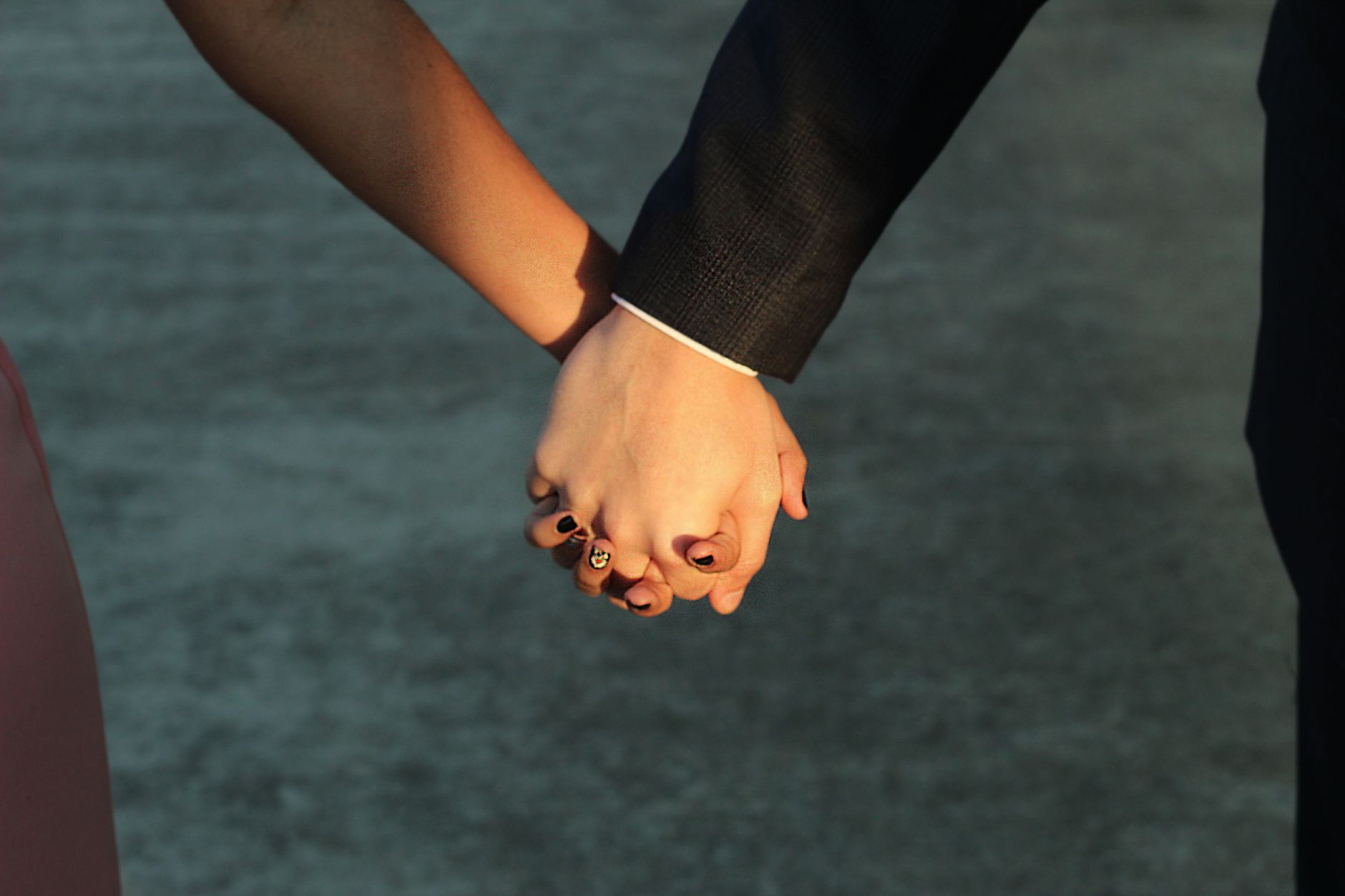 Twee mensen houden buiten elkaars hand vast