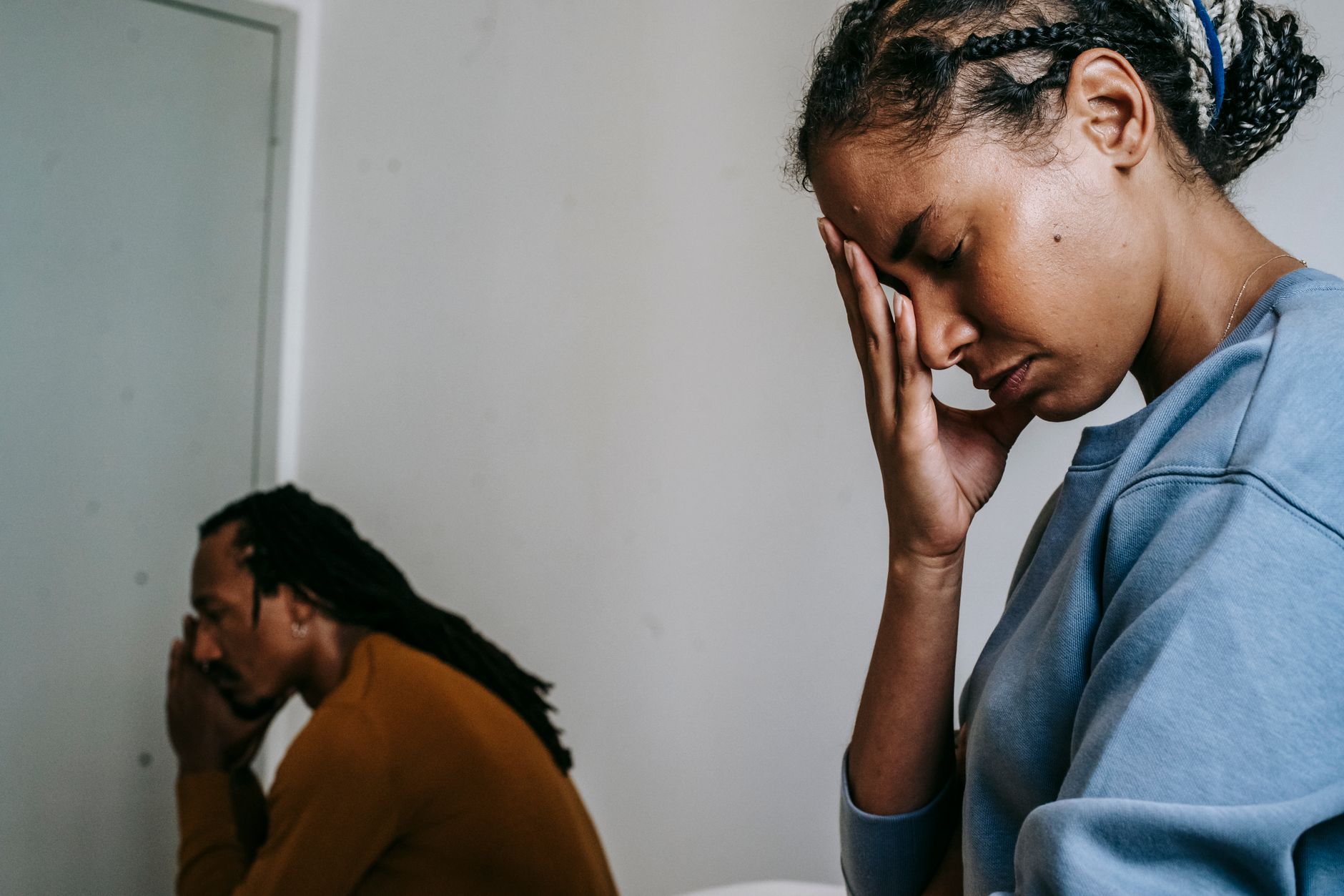 Man en vrouw zitten thuis naast elkaar, allebei in gedachten